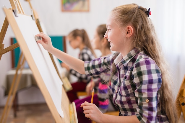 Children draw on an easel in art school.