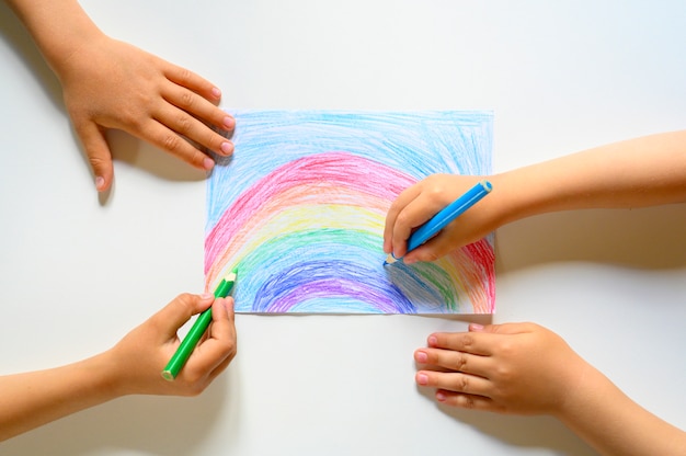 Children drawing a rainbow on white background