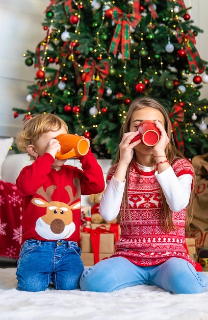 子供たちはクリスマス ツリーの近くでお茶を飲む