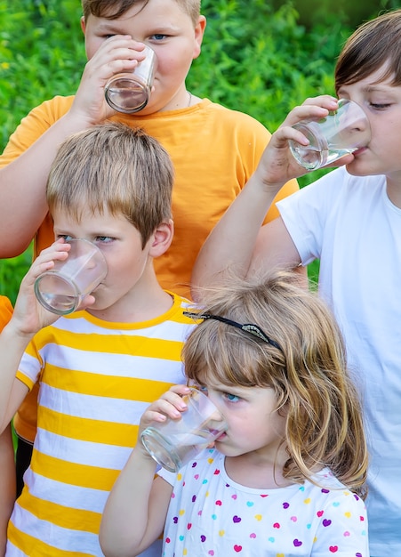 Children drink water outside together.