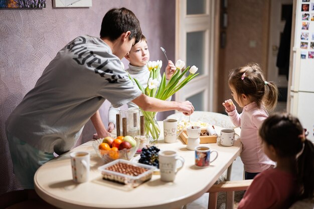 Children eat fruits and desserts drink tea at home in the evening kitchen