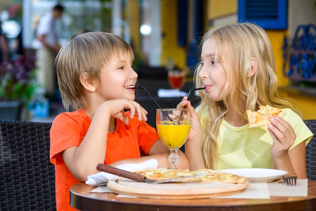 Children eat pizza and drink juice outdoor
