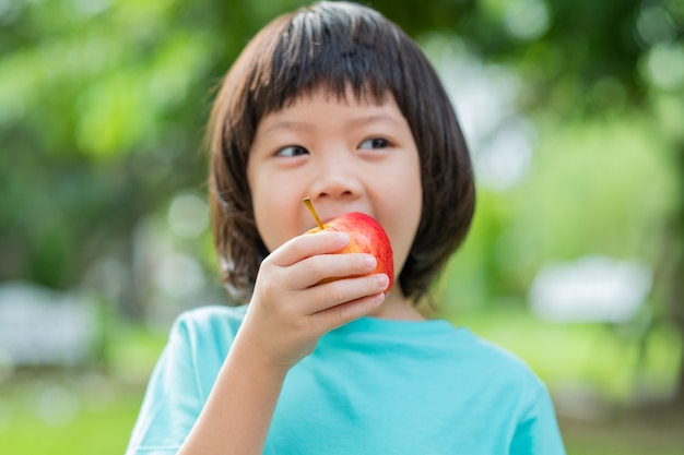 Children eating an apple in green nature