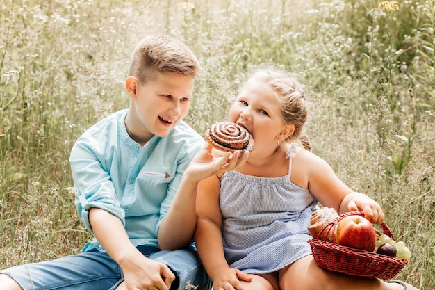 屋外で昼食をとる子供たち春の庭でピクニックをする子供たち未就学児の女の子と学校の男の子は夏の公園で食べたり飲んだりします