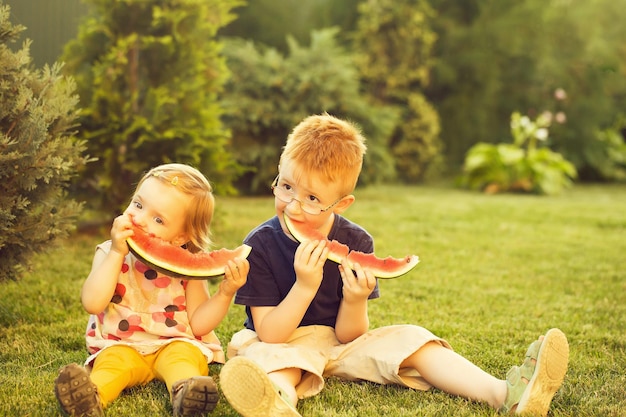 Фото Дети едят красный арбуз на траве