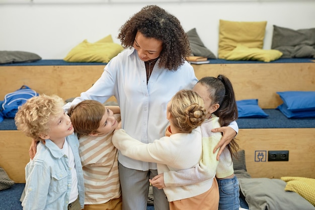 Foto bambini che abbracciano un'insegnante sorridente