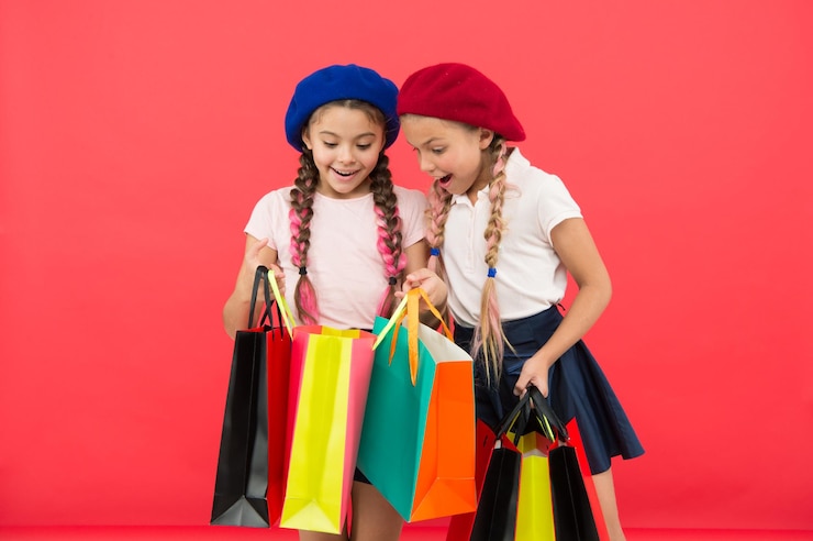 Photo children enjoy shopping red background visiting clothing mall discount and sale concept kids cute girls hold shopping bags shopping discount season special offer great day for shopping