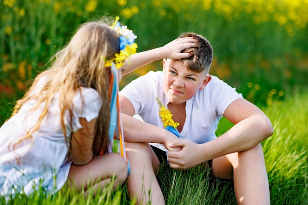 날씨를 즐기는 아이들 형제 자매는 쪼그리고 앉아 하늘 아래 꽃과 풀과 함께 들판에서 이야기합니다