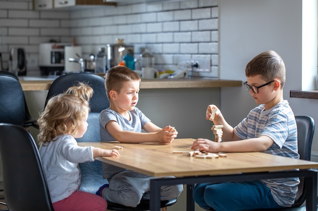 I bambini giocano con entusiasmo a un gioco da tavolo con cubetti di legno sul tavolo.