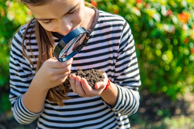 I bambini esaminano il terreno con una lente d'ingrandimento messa a fuoco selettiva