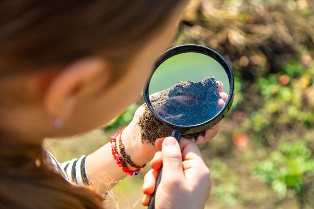 Photo children examine the soil with a magnifying glass selective focus