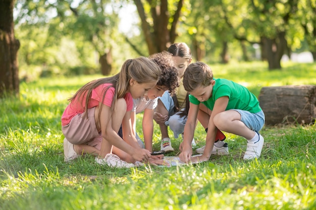 Children exploring map on green lawn