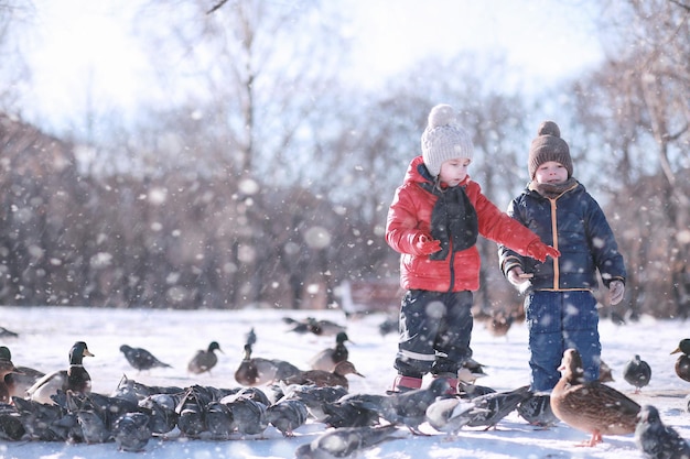 Children feed birds in the park in winter