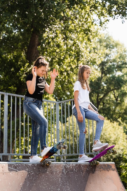 Children friendship girls friends ready for ride on penny board\
on skateboard park playground sports equipment for kids extreme\
lifestyle