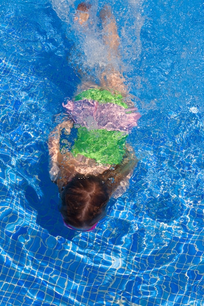 children gilr swimming underwater in blue pool