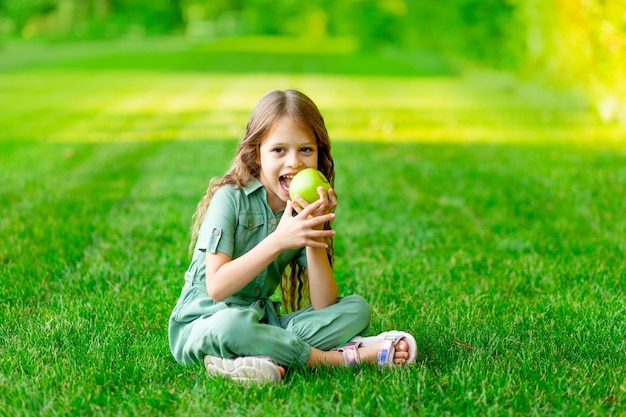 Children a girl and a blonde boy kiss behind a big red heart in summer on a lawn on green grass the concept of a valentine's day holiday space for text