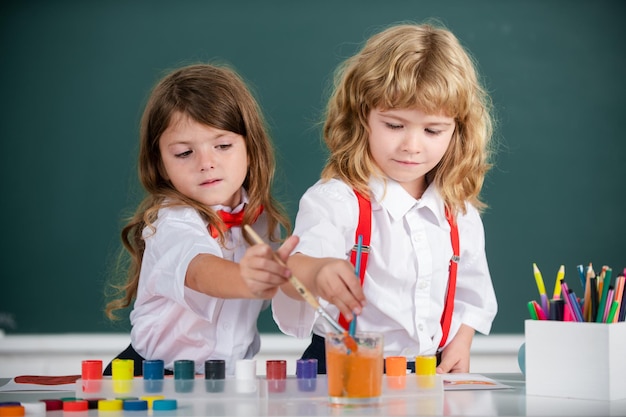 Children girl and boy drawing with coloring pens Cute school kids painting in class at school Painting lesson drawing art Kids art creativity children concept