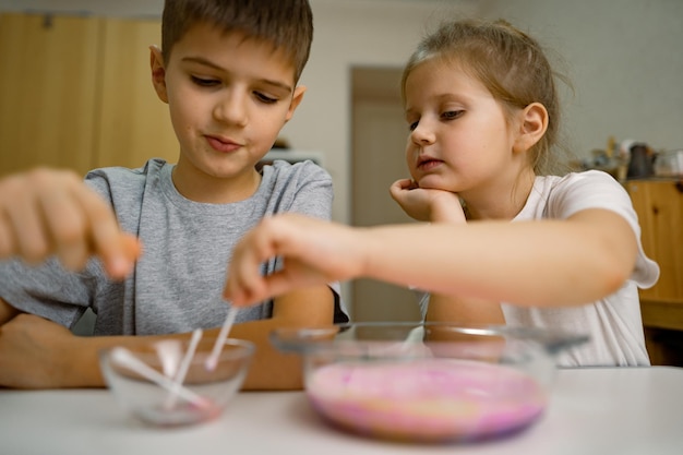 Photo children girl boy at home experimenting with milk and paints