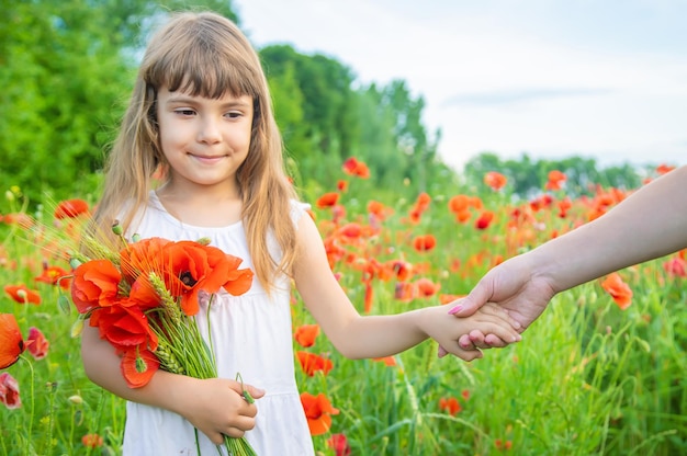 Children girl in a field with poppies selective focus