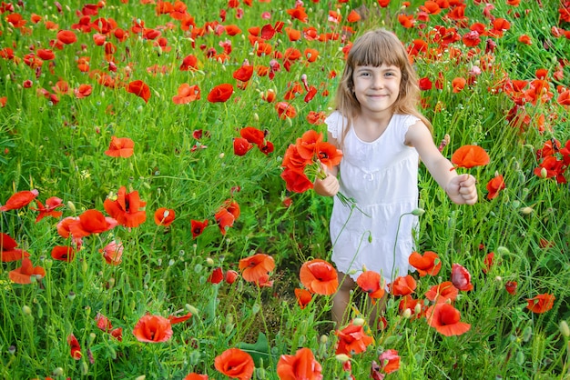 Children girl in a field with poppies.