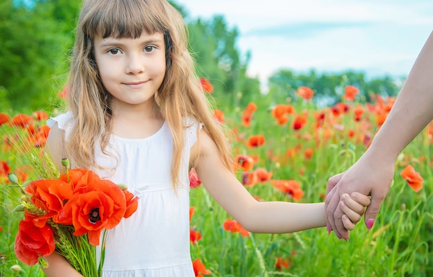 Children girl in a field with poppies.