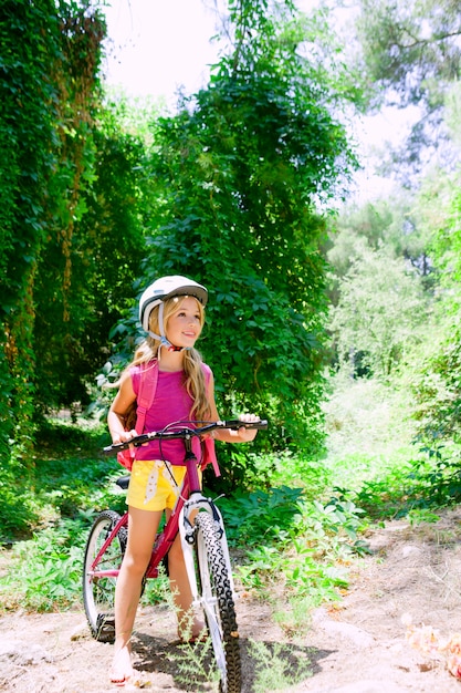 子供の女の子が森の笑顔で屋外自転車に乗って