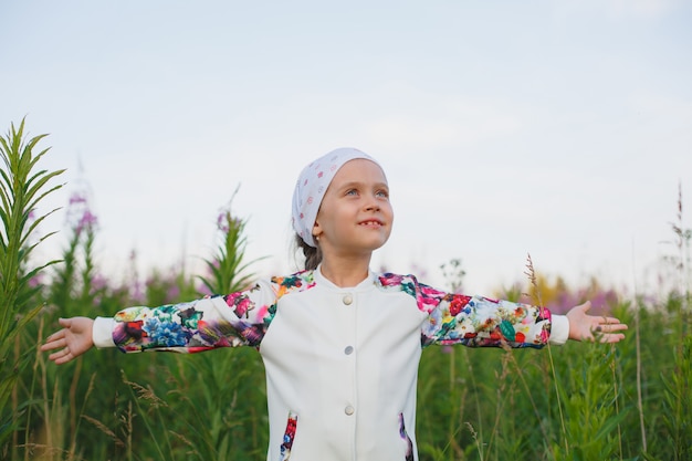 Children girl with open arms on meadow