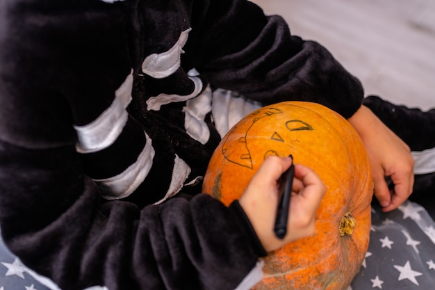 Photo children in halloween costumes paint pumpkins boy decorate the house for holiday celebrating at home