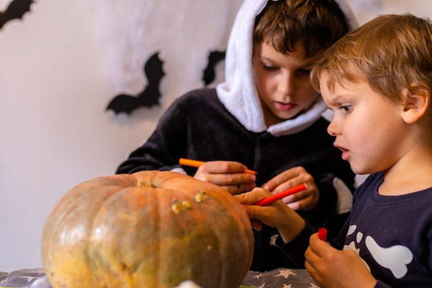 Children in halloween costumes paint pumpkins boy decorate the house for holiday celebrating at home