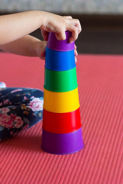 Children hands make Pyramid using colorful stacking cups