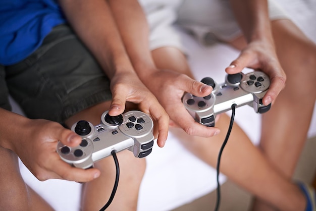 Foto bambini mani e controller di videogiochi in una casa per abbonamento a giochi o intrattenimento primo piano da sopra gamepad zoom e gamer boy bambini a casa con competizione o sfida di esports