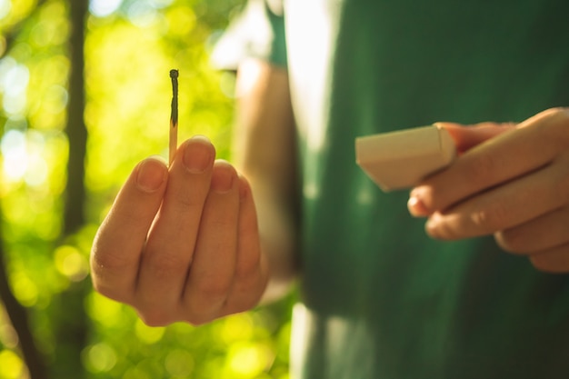 Photo children hands with burning match in the dry forest. danger of forest fire, environment disaster concept photo