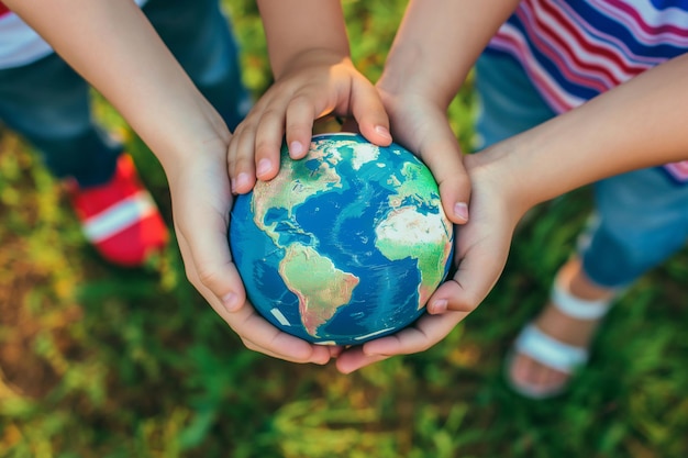 Photo children happily holding a globe in their hands on grass