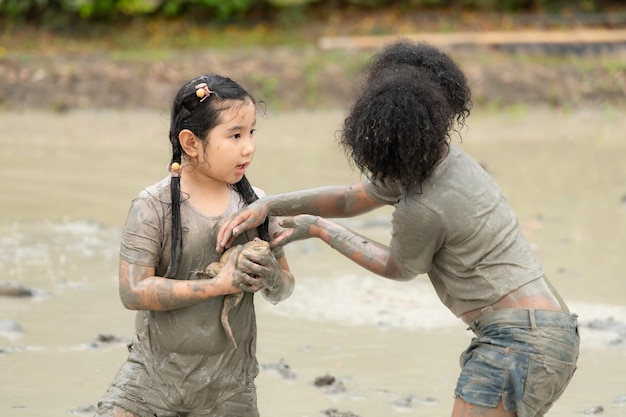 Children have fun playing in the mud in the community fields and catching a frog in a muddy field