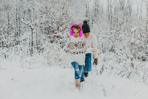 Children have fun playing in the snow. boy and girl running around in winter park. winter holidays