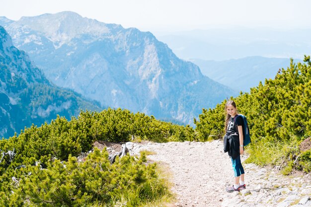 Children hiking on beautiful summer day in alps mountains austria, resting on rock and admire amazing view to mountain peaks. active family vacation leisure with kids.outdoor fun and healthy activity