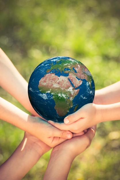 Дети держат в руках голубую планету на зеленом весеннем фоне Концепция праздника День Земли Элементы этого изображения предоставлены НАСА