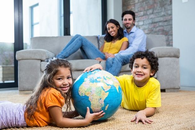 Children holding globe on carpet in living room