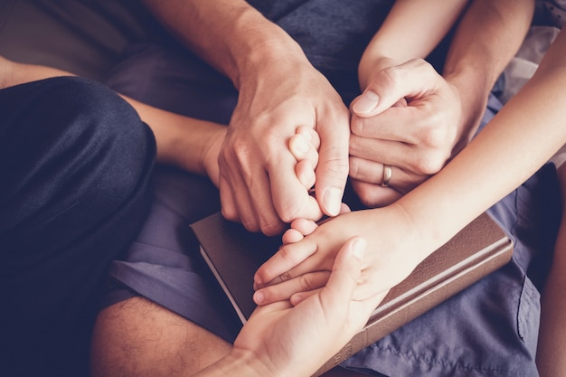 Children holding hands and praying with their parent at home, family pray, Having faith and hope.