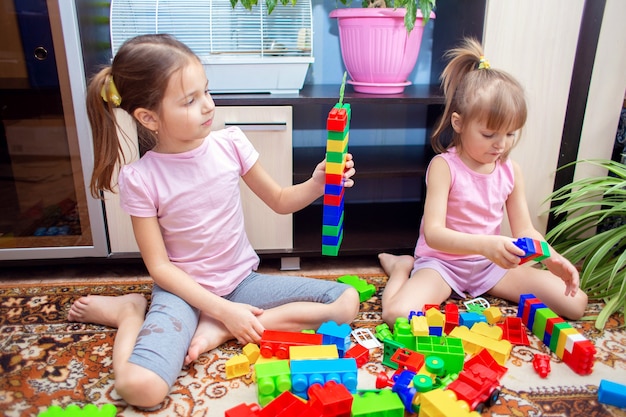 Children at home play with a plastic colored construction set