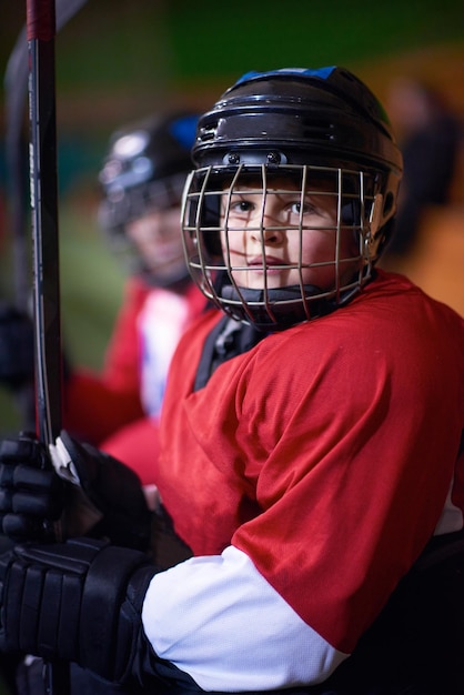 Foto giocatori di hockey su ghiaccio per bambini, gruppo di persone, amici di squadra che aspettano e si rilassano sulla panchina per iniziare la partita