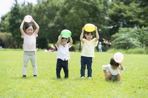 写真 草の上に風船を持つ行の子供