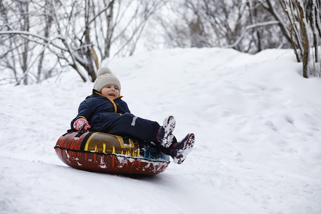 写真 冬の公園の子供たち。子供たちは遊び場で雪で遊ぶ。彼らは雪だるまを彫刻し、丘を滑り降ります。