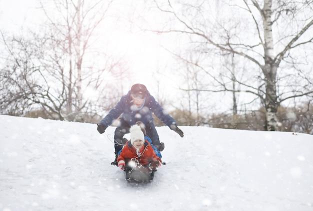 写真 冬の公園の子供たち。子供たちは遊び場で雪で遊ぶ。彼らは雪だるまを彫刻し、丘を滑り降ります。