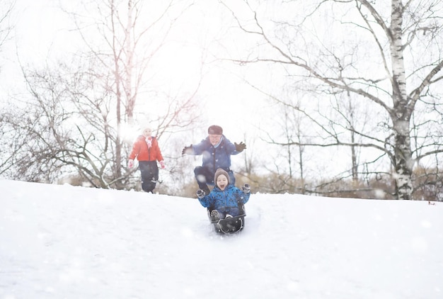 冬の公園の子供たち。子供たちは遊び場で雪で遊ぶ。彼らは雪だるまを彫刻し、丘を滑り降ります。