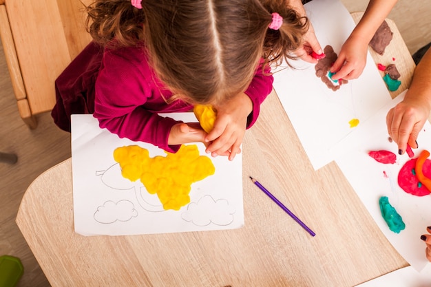 Children is playing with modeling clay on the table