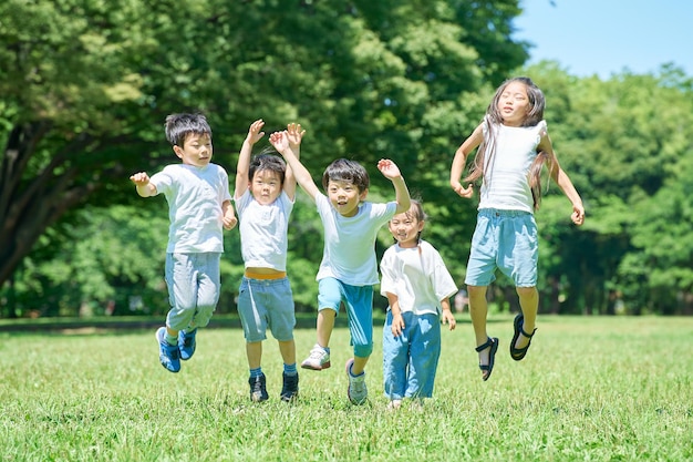 写真 晴れた日に公園で一緒にジャンプする子供たち