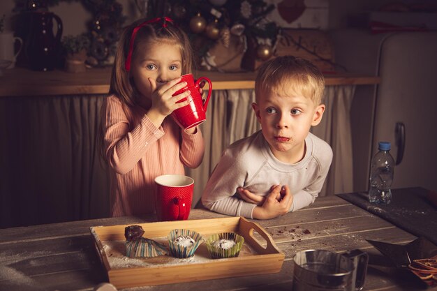 キッチンの子供たちはクッキーを準備しています。クリスマスの飾り、家族の伝統、クリスマス料理、休日の前夜。