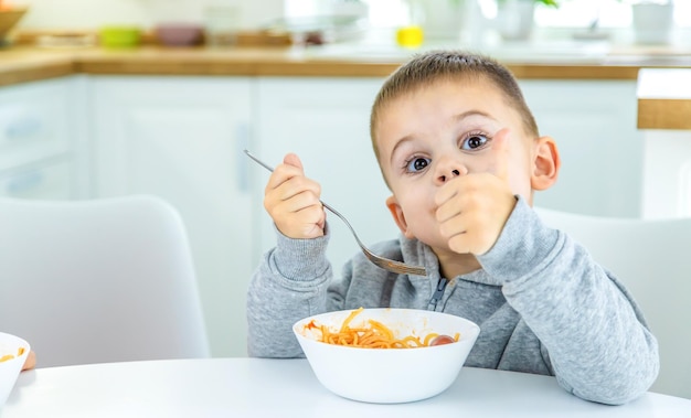 パスタの選択的な焦点を回すテーブルのキッチンの子供たち