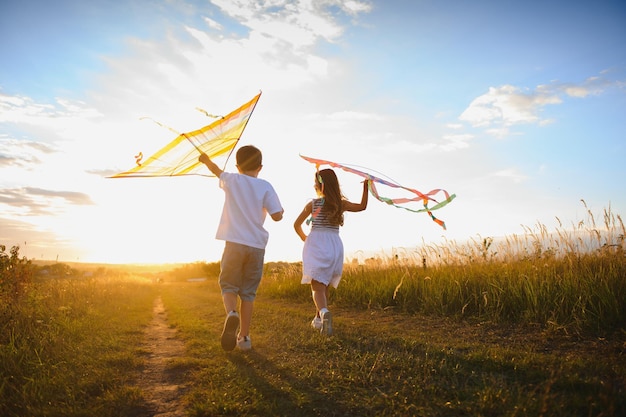 Children launch a kite in the field at sunset